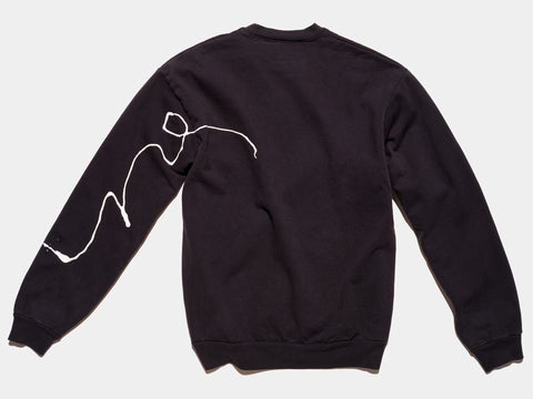 100% cotton black sweatshirt, perfectly cut, has scrawled, drippy white hand-painted line on back of left sleeve, a continuation of the line from the front of the sweatshirt